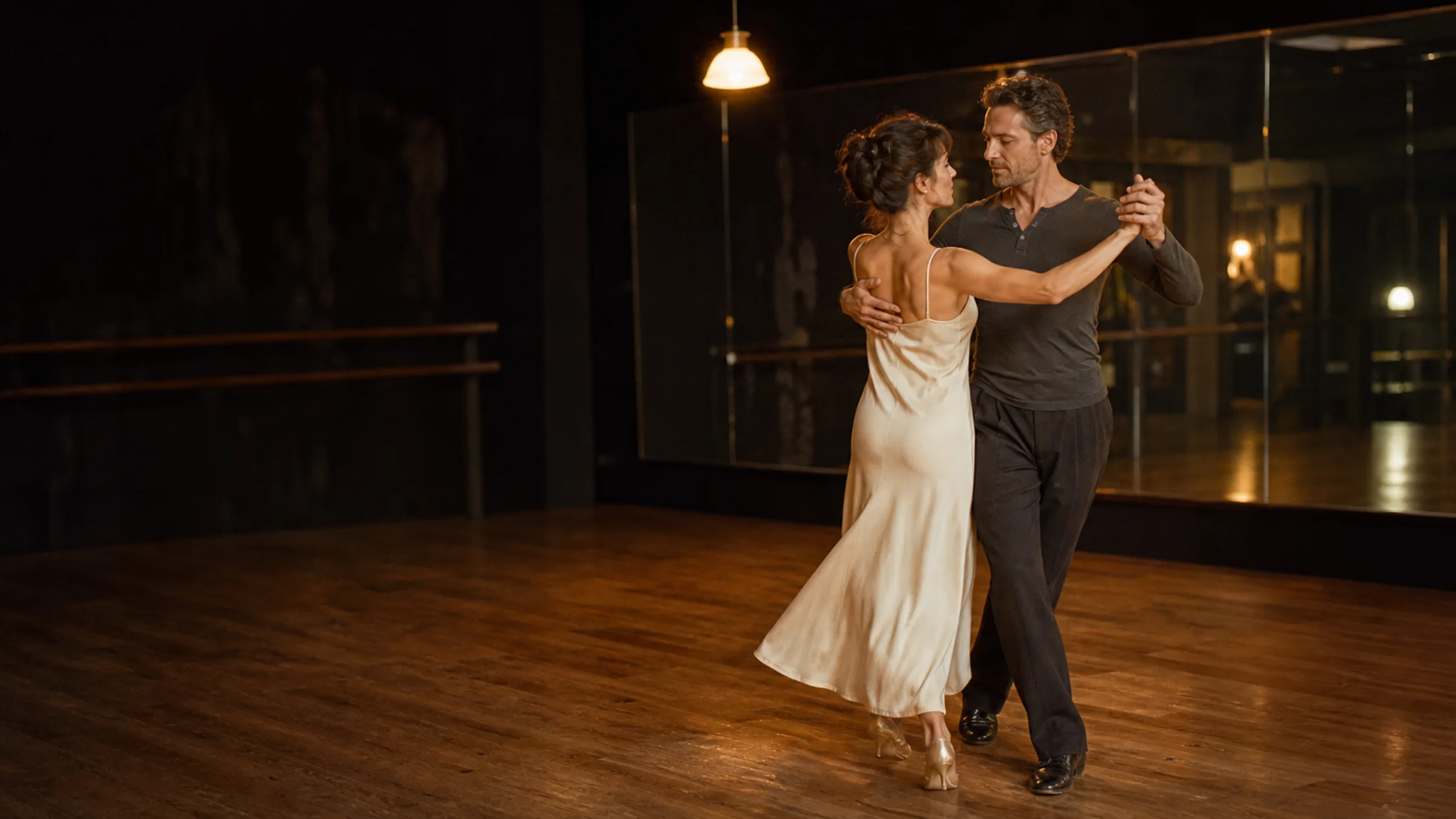 A couple in a private ballroom lesson on a warm wood floor at S-Style Dance Team
